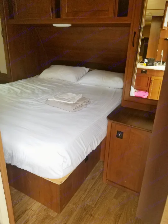 Cozy RV rental bedroom with fresh linens & a mirrored view of the kitchen, perfect for your next adventure.. Jayco White Hawk Ultra Lite 2015