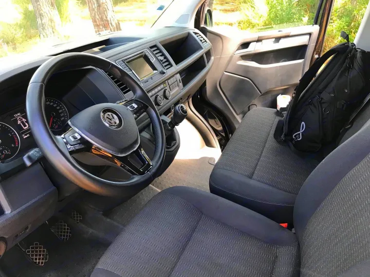 Start your adventure! View of a VW van's driver cockpit & passenger seat in an RV rental, ready for the road.. Volkswagen Caravelle Long 2019