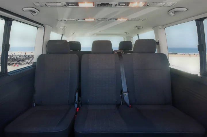 Comfortable rear seats of an RV rental van, offering a picturesque beach and ocean view through the windows.. Volkswagen Caravelle Long 2019