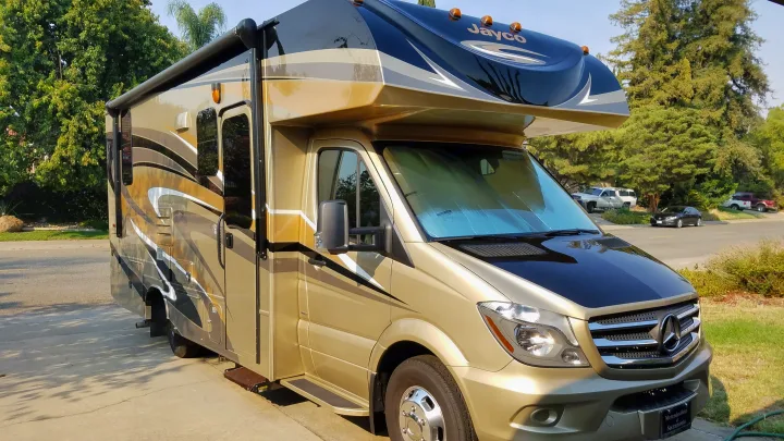 This sleek gold and black Class C RV rental, a Mercedes-Benz model, is parked outdoors on a bright day.. Jayco Melbourne 2017