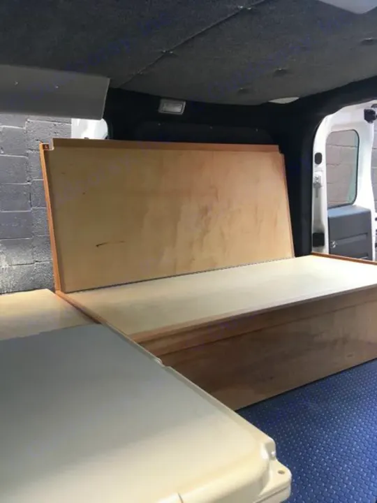 Custom camper van interior. Wooden bench/bed & flat surface visible for RV rental adventures.. ram promaster city 2018