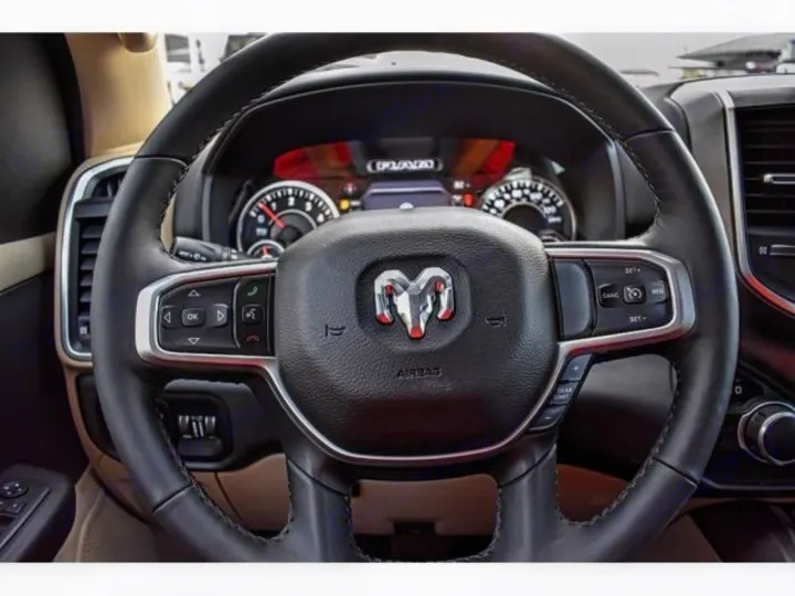 Detailed view of an RV rental's modern steering wheel, featuring integrated controls for infotainment & driving assistance.. ram 1500 bighorn 2019