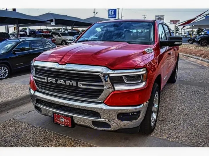 A bold red Ram pickup truck shines at a vehicle lot. Great for hauling gear on your next adventure, complementing an RV rental.. ram 1500 bighorn 2019