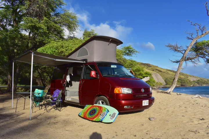 Maroon VW camper van with pop-top & awning on a sandy beach. Ideal for your next RV rental adventure!. Volkswagen Westfalia 2001
