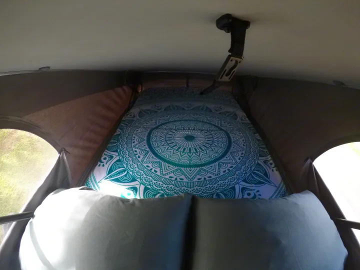Cozy RV rental sleeping area with a teal mandala bed and pillows, seen through mesh windows. Perfect for camping adventures.. Volkswagen Westfalia 2001