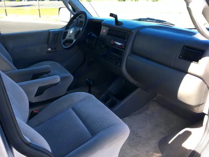 Spacious RV rental interior showing light gray front seats, dashboard, and steering wheel for your next road trip.. Volkswagen Westfalia 2002