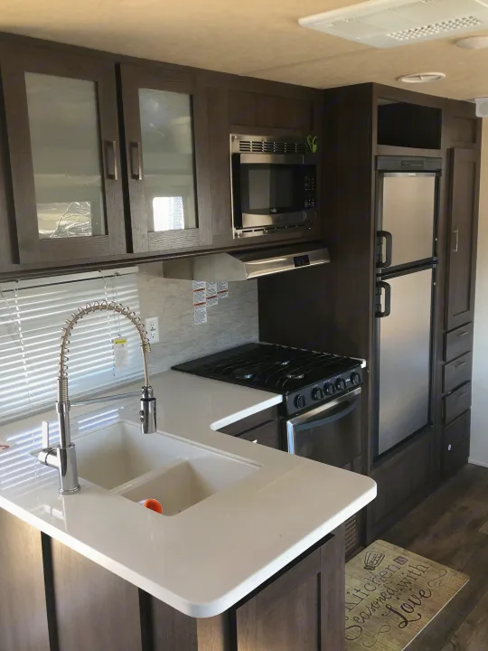 Kitchen with 3 range stove, sink, refrigerator and mircowave . Forest River Wildwood 2018