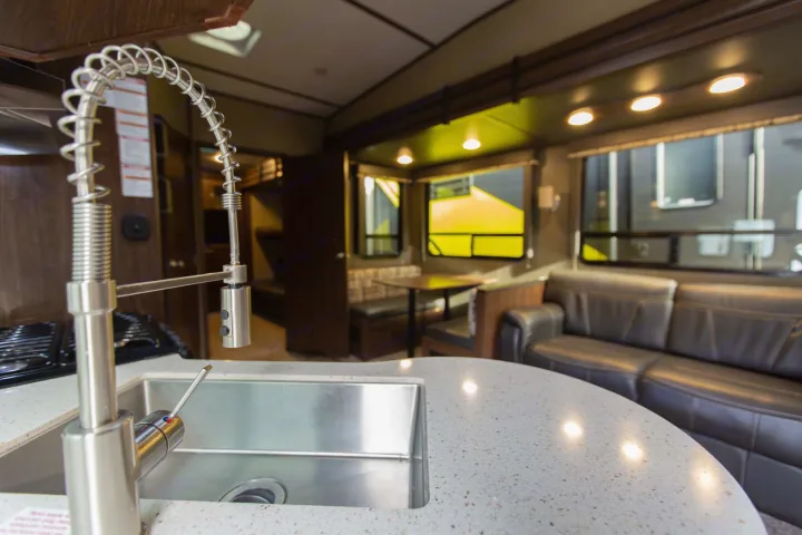 Spacious RV rental interior featuring a modern kitchen with sink, dining booth, and comfortable sofa for your travels.. sprinter keystone 2018
