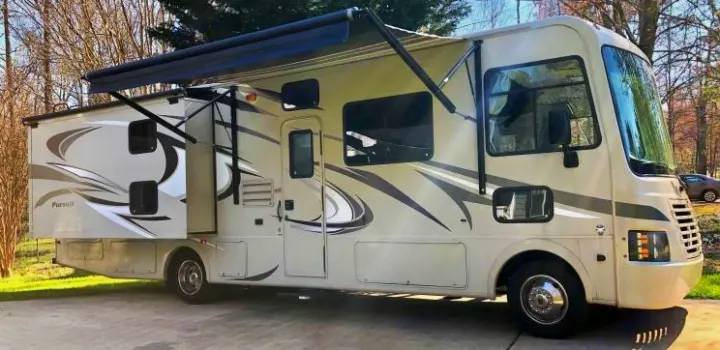 This large, light-colored Class A RV rental features an extended awning and rear slide-out, ready for travel.. Coachmen Pursuit 2014
