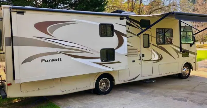Spacious Class A RV rental with its slide-out and awning extended, parked on pavement for your next adventure.. Coachmen Pursuit 2014