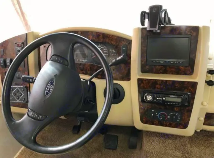 Driver's view of a Ford RV rental dashboard featuring the steering wheel, gauges, infotainment screen, and climate controls.. Coachmen Pursuit 2014