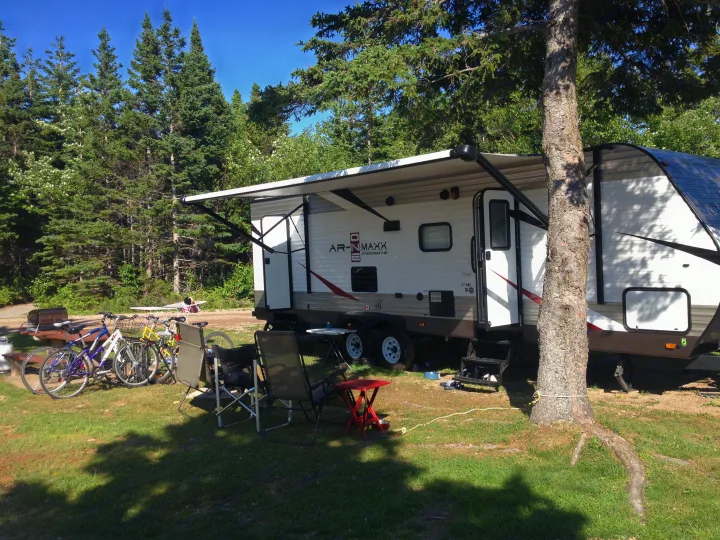 Spacious RV rental parked at a sunny forest campsite, complete with bicycles, outdoor chairs, and an extended awning.. Starcraft Ar-One MAXX 2016