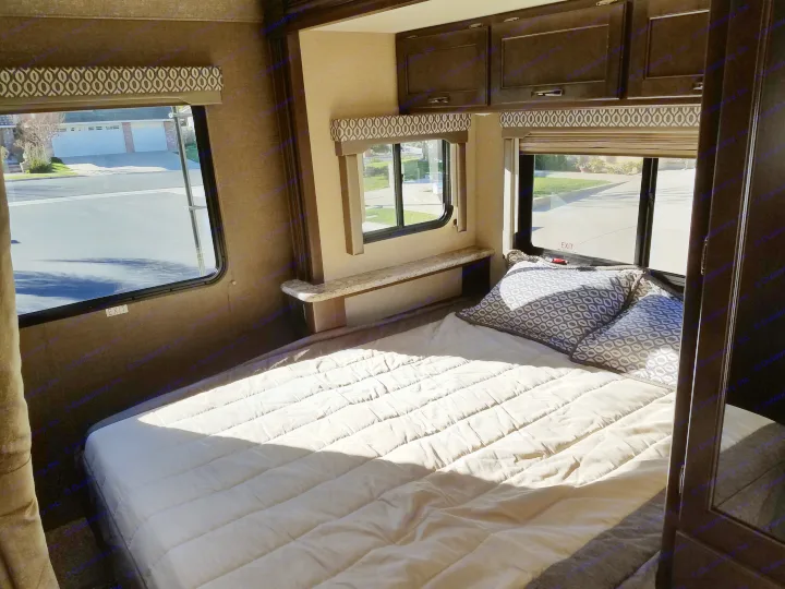 Comfortable RV rental bedroom with ample sunlight, a cozy bed, and practical storage cabinets. Enjoy the view!. Thor Freedom Elite 2019