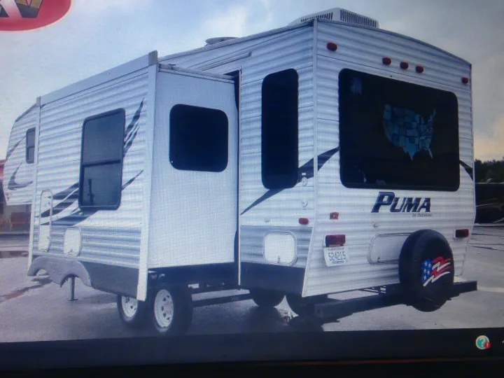 Rear/side view of a white Puma travel trailer, an excellent RV rental option with an extended slide-out.. Palomino Puma 2010