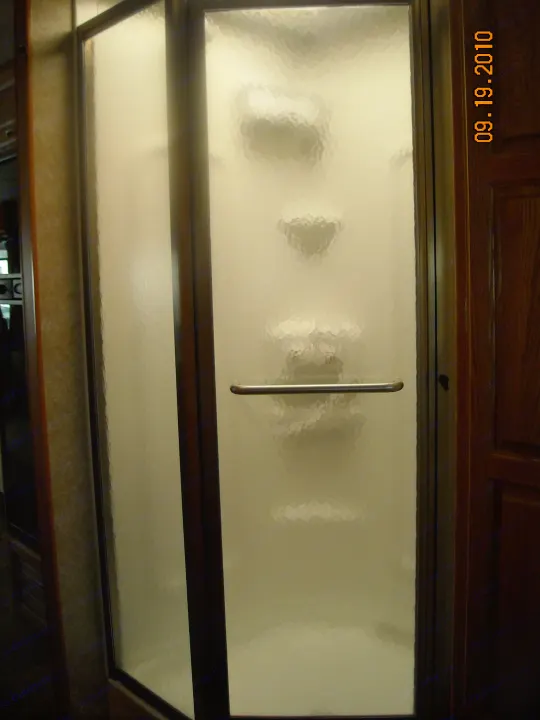 RV rental shower: A frosted glass stall with a silver handle, designed for privacy in compact RV bathrooms.. Thor Motor Coach Hurricane 34N 2006