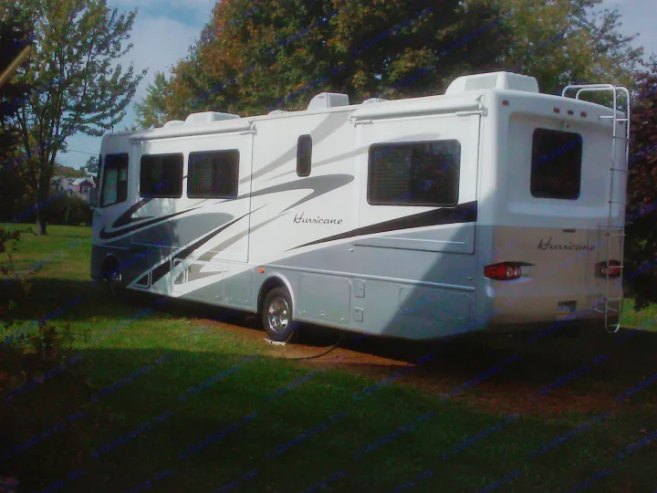 A large white and gray Hurricane motorhome, ideal for an RV rental adventure, parked on grass.. Thor Motor Coach Hurricane 34N 2006