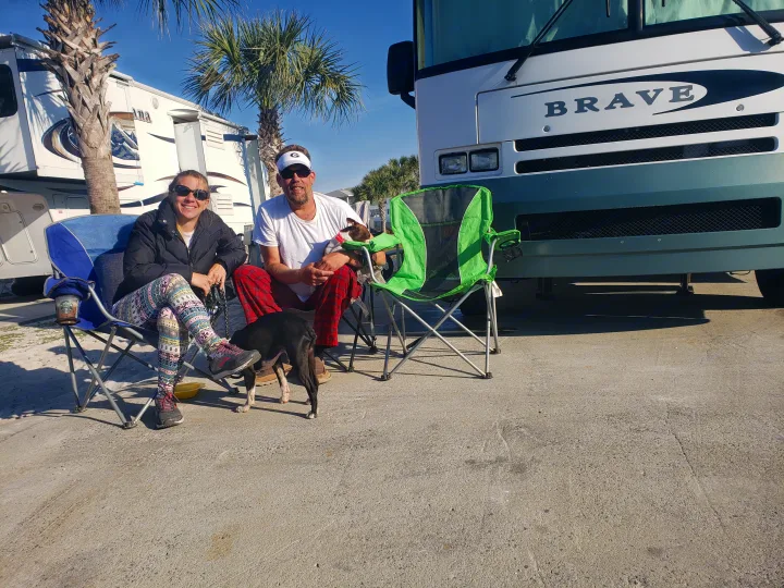 Happy couple and dogs enjoy their RV rental stay, featuring a "Brave" motorhome at a sunny camp.. Winnebago Brave 2001