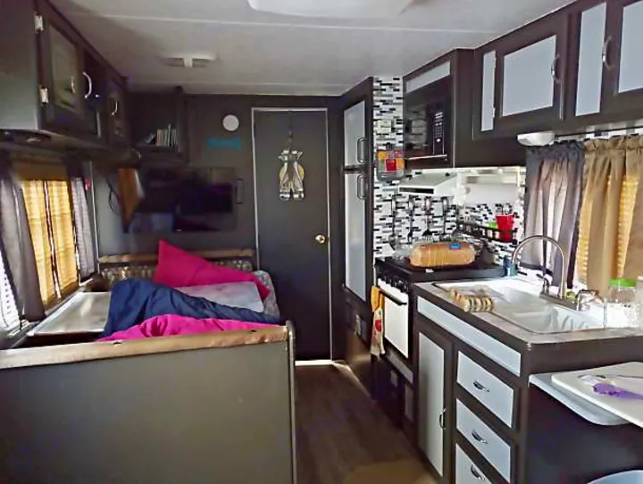 Modern RV rental interior showcasing a compact kitchen with appliances and a cozy living/sleeping area.. Skyline Nomad 1996