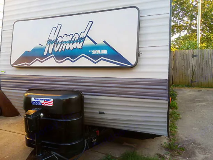 Side of a gray Nomad by Skyline travel trailer, displaying its logo and propane tank. Consider this RV rental for your next trip.. Skyline Nomad 1996