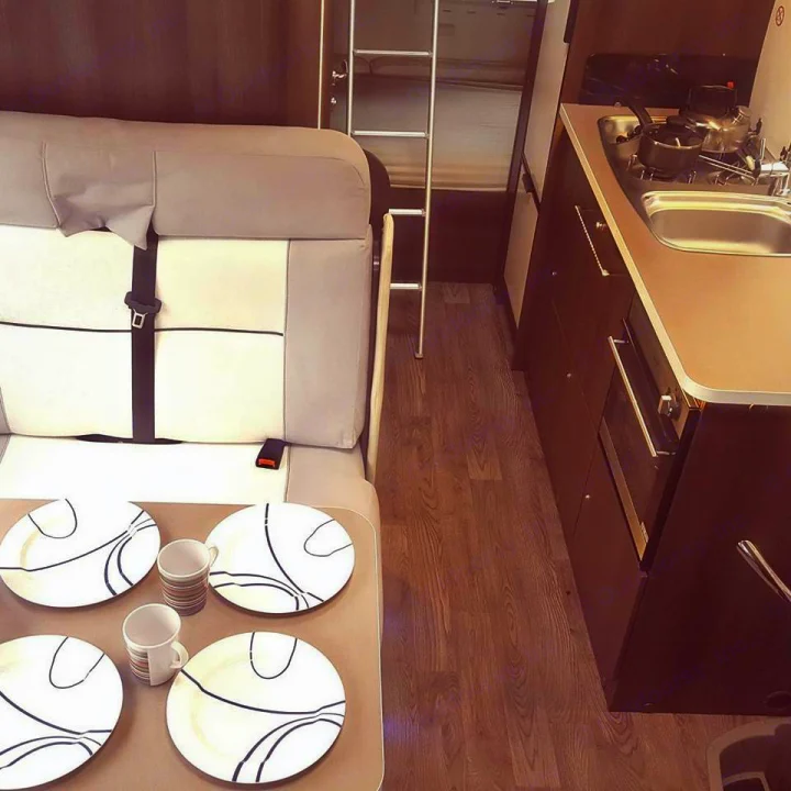RV rental interior: compact kitchen, dining table with dishes, and a ladder to an overhead bunk. Travel ready!. Other Transit Motorhome 2018