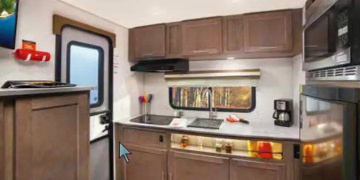 Compact RV rental kitchen, featuring a sink, microwave, refrigerator, and cabinetry. Designed for comfortable living on the road.. Forest River Other 2019
