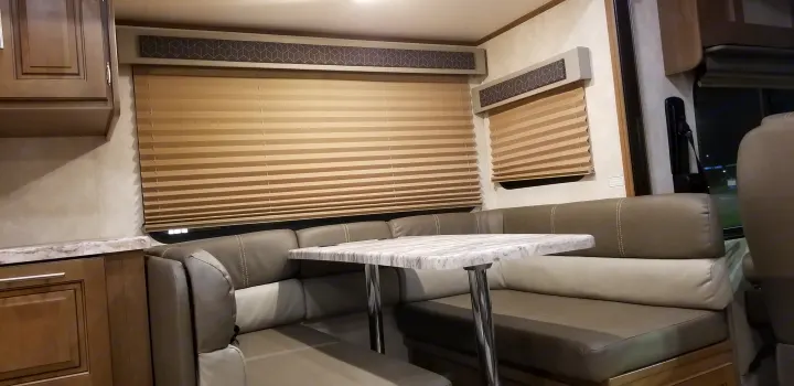 Cozy RV rental dinette with U-shaped booth seating, modern table, and closed blinds, perfect for dining or relaxing.. Forest River Fr3 2021