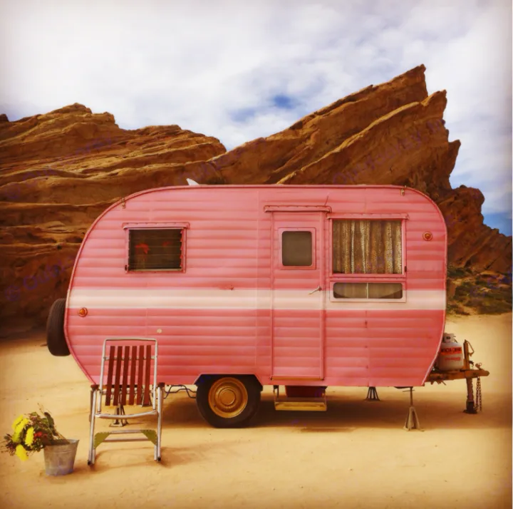 Vintage pink RV rental parked in front of dramatic desert rocks. Perfect for a retro adventure.. Pleasurecraft Canned Ham 1956