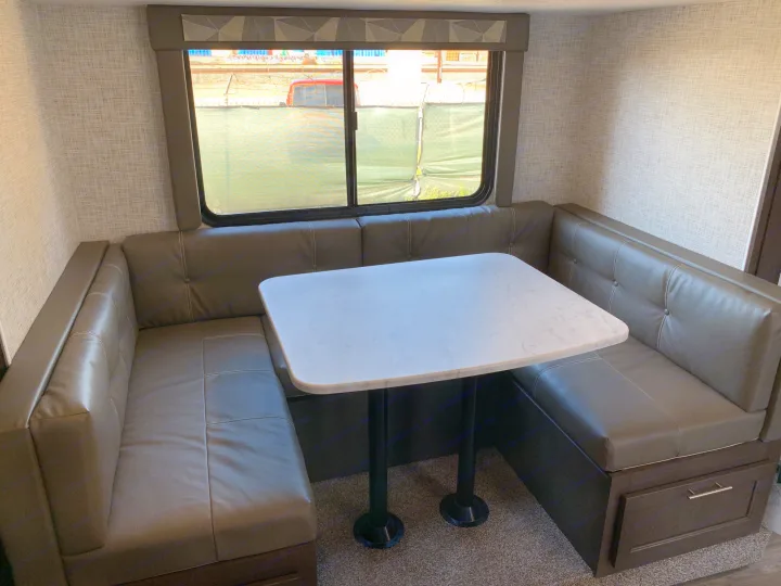 RV rental interior: cozy U-shaped dinette with faux leather seating and a white marble-look table, great for meals.. Forest River Cruise Lite 2020
