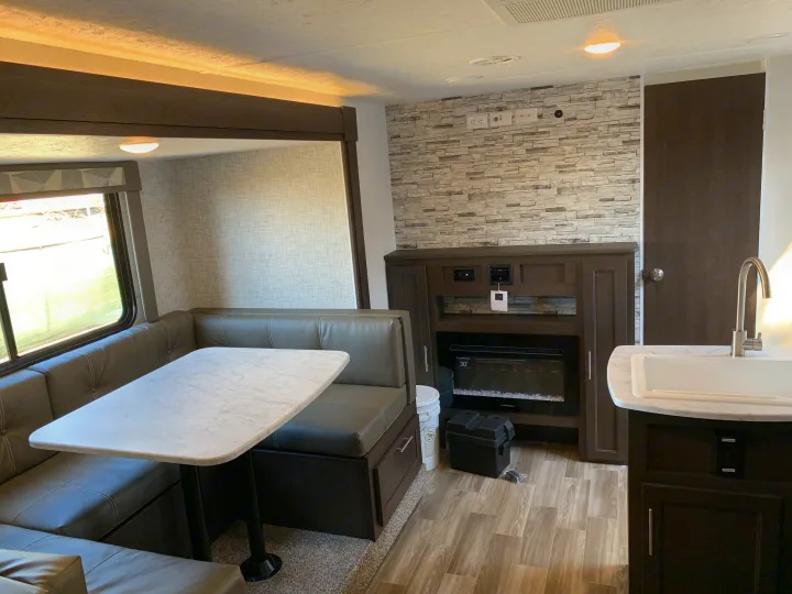 Tour this RV rental interior: featuring a cozy dinette, kitchen area, and entertainment center with fireplace.. Forest River Cruise Lite 2020