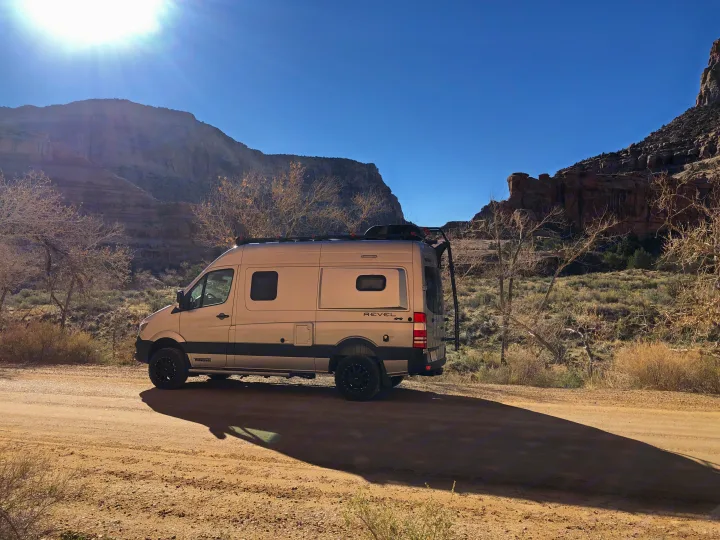 Winnebago Revel 4x4 rv rental parked on a desert dirt road with mountains under a sunny sky, casting a long shadow.. Winnebago Mercedes Sprinter 2019