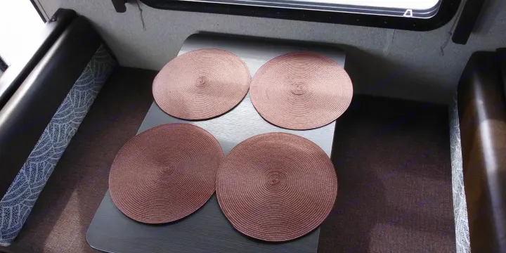 RV rental dinette: a dark table holds four bronze placemats. Booth seating with patterned fabric borders the cozy space.. Keystone RV Springdale 2018