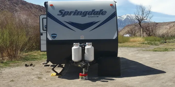Springdale RV rental, a travel trailer, set up for camping with propane tanks & snowy mountain views.. Keystone RV Springdale 2018