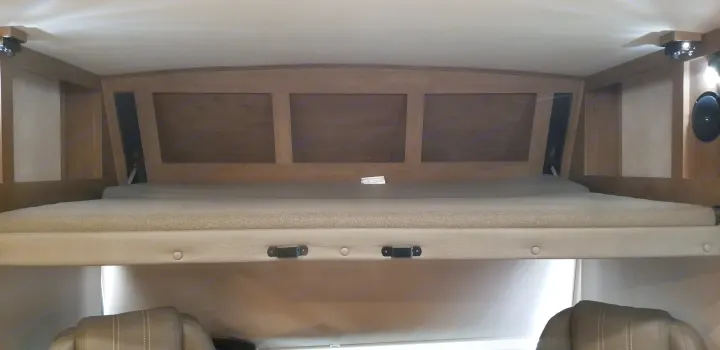 Explore a cozy RV rental's cab-over bunk. This well-lit sleeping area offers built-in storage and comfort for travel.. Forest River Fr3 2021
