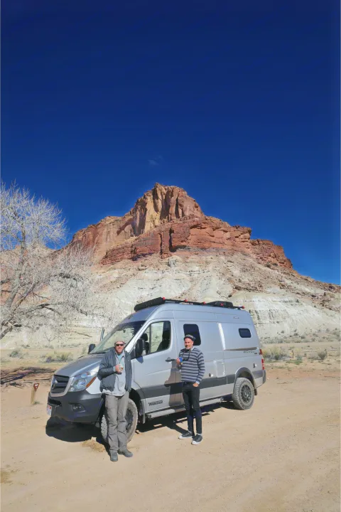 Two men enjoy their rv rental, a silver Winnebago Revel, amidst stunning desert rock formations. Perfect for adventure travel.. Winnebago Mercedes Sprinter 2019