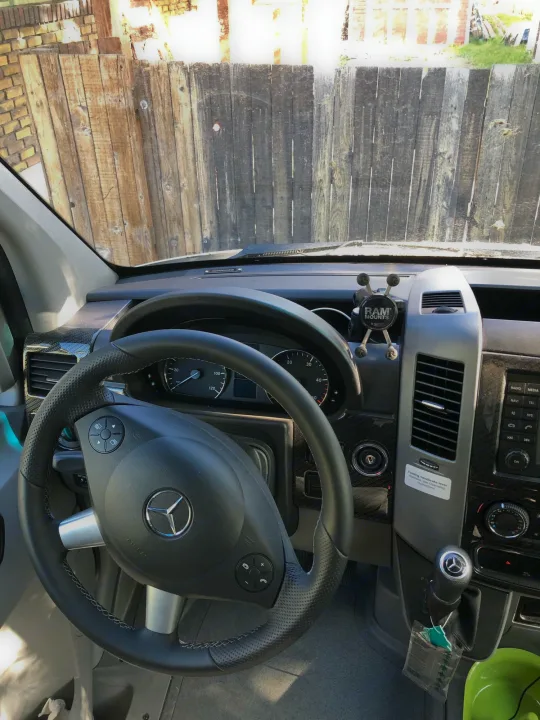 RV rental interior: Mercedes-Benz dashboard, steering wheel, and RAM Mount phone holder. A navigation system is also visible.. Winnebago Mercedes Sprinter 2019