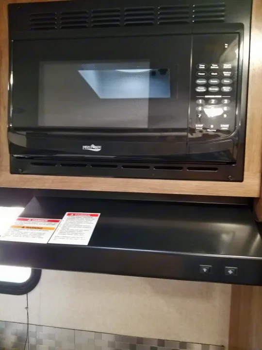 Modern High Pointe microwave and range hood in an RV rental kitchen, offering convenient cooking and ventilation.. Jayco Jay Feather 2018