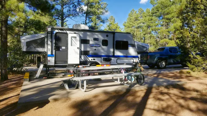 Jay Feather RV rental set up in a sunny forest campsite with picnic table, truck, ready for outdoor adventures.. Jayco Jay Feather 2018
