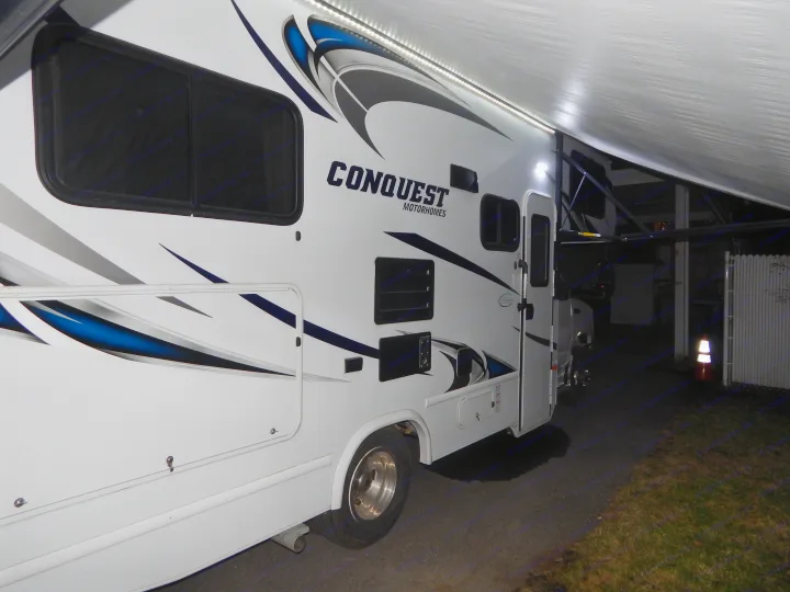 White Conquest motorhome RV rental, brightly lit by its LED awning at night. Ready for your next adventure!. Gulf Stream Conquest 2016