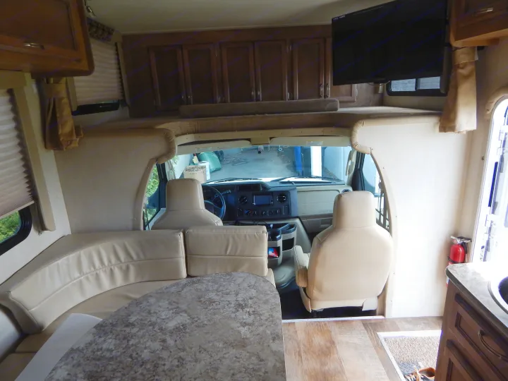 Step inside this RV rental, showcasing its comfortable dinette, driver's area, and overhead bunk. Perfect for road trips!. Gulf Stream Conquest 2016