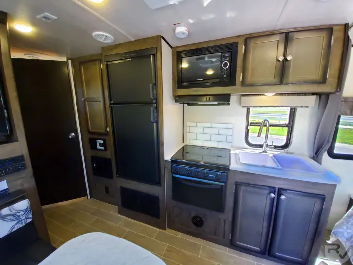 Modern RV rental kitchen with stove, microwave, sink, and fridge for comfortable travels.. Heartland Wilderness 2020