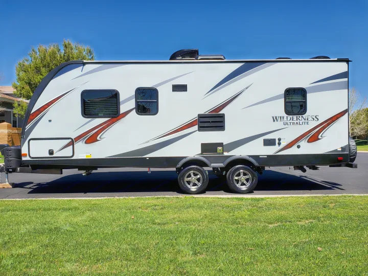 This gray 'Wilderness Ultralite' travel trailer, perfect for an RV rental, features dual axles and modern design.. Heartland Wilderness 2020