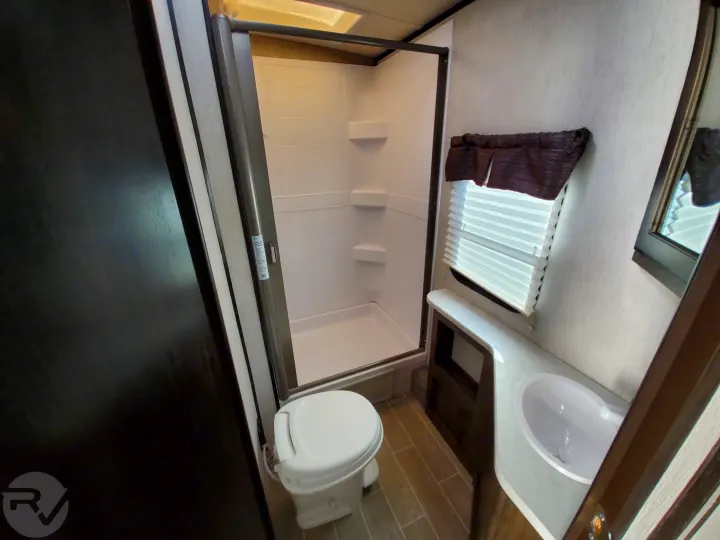 Inside an RV rental: a compact bathroom with a bright shower, toilet, and sink, designed for comfortable travel.. Heartland Wilderness 2020