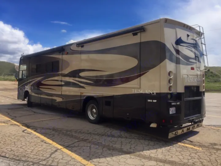 This impressive tan & brown Damon Tuscany motorhome, ready for RV rental, is parked outdoors in a lot with hills.. Damon Tuscany 2008
