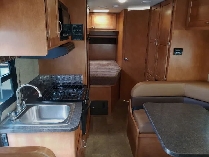Spacious RV rental interior: well-equipped kitchen, comfortable dining booth, and dedicated sleeping area.. Winnebago Minnie Winnie 2018