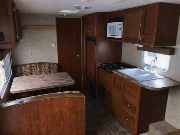 Spacious RV rental interior featuring a kitchen with sink, stove, microwave, and dinette seating. Ample storage cabinetry.. Eclipse Recreational Vehicles Maveric 2011