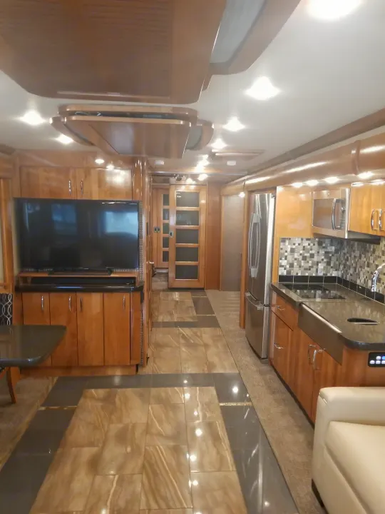 Luxury RV rental interior showcasing a modern kitchen, built-in TV area, and warm wood finishes, designed for comfort.. Fleetwood American Eagle 2019