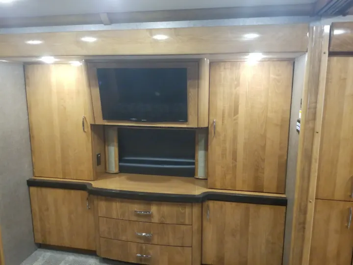 This RV rental features a built-in wood entertainment unit with a flat-screen TV, ample storage cabinets, and drawers.. Fleetwood American Eagle 2019