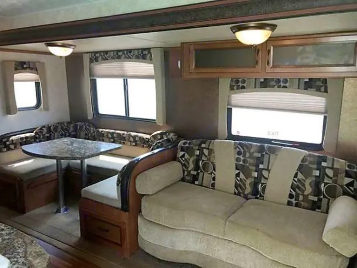 Spacious RV rental interior featuring a comfy U-shaped dinette, sofa, and overhead storage. Ideal for trips.. Gulf Stream Conquest 2014