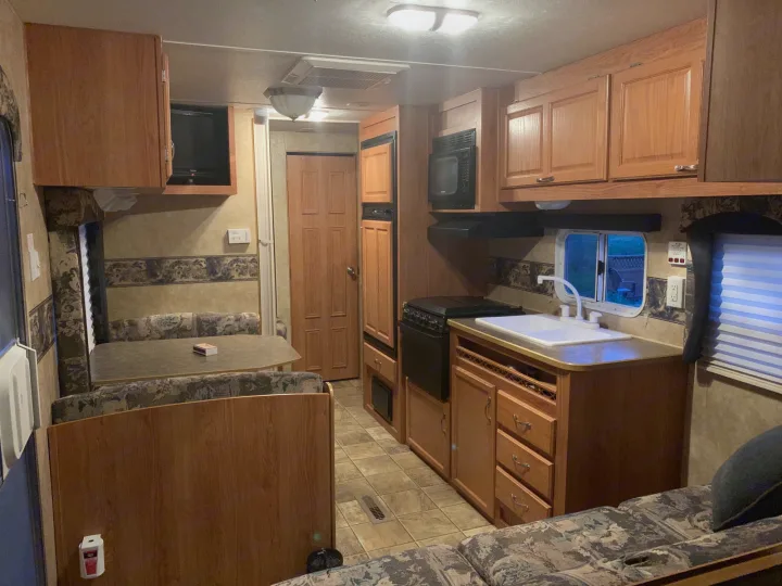 Discover the convenience of this RV rental's well-equipped interior, featuring a kitchen, dining booth, and cozy living space.. Jayco Jay Flight 2007