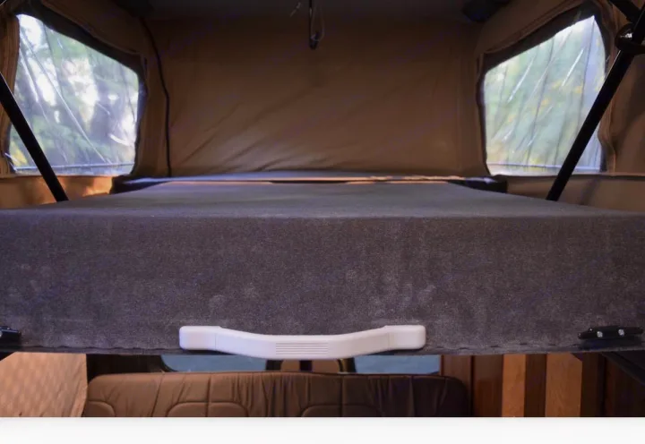 Elevated bed in this RV rental pop-top camper, with clear windows offering outdoor views.. Mercedes-Benz Sprinter 2016